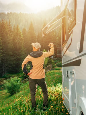 man enjoying the morning sun near an rv in a mountain forest while  national park RV camping in the west